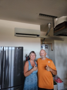 Man and woman standing in garage under mini split ac unit